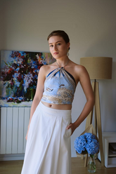 a lady in an off the shoulder top and a white pleated dress